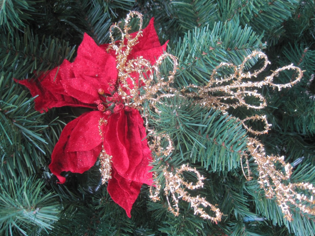 I like to have interesting spots on my tree, which entails combining some of my decorations together. I take my gold tinsel circle pick and zip-tie a plain red velvet poinsettia to it. This is a nice contrast of sparkle and simple and adds interest.
